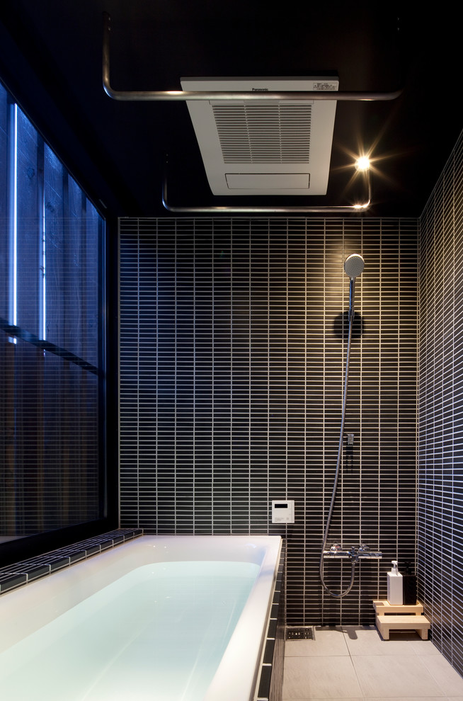 Exemple d'une salle de bain moderne avec une baignoire d'angle, une douche ouverte, un carrelage noir, un mur noir et un sol beige.