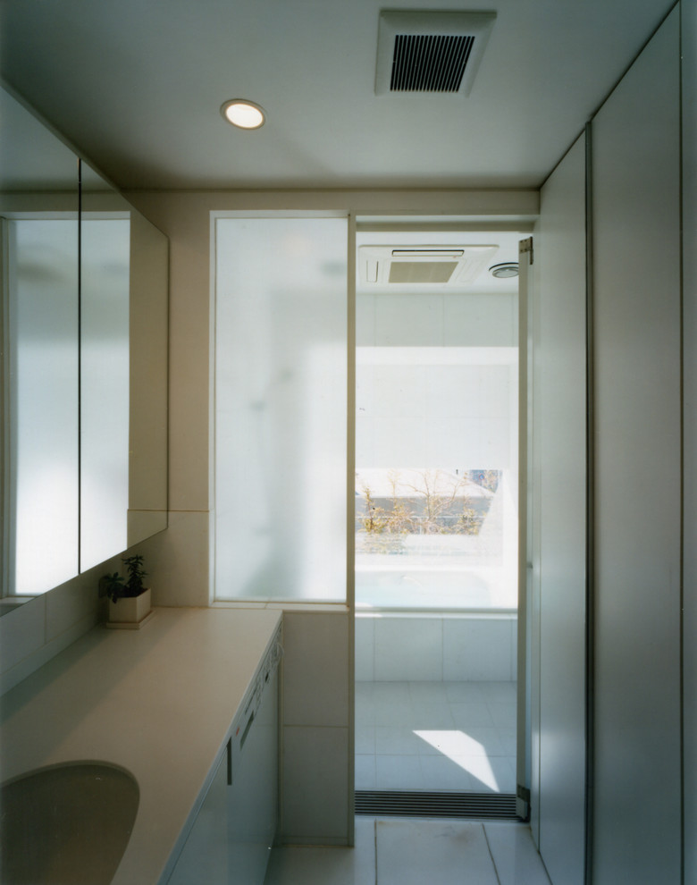 Bild på ett mellanstort orientaliskt vit vitt badrum, med luckor med profilerade fronter, vita skåp, ett platsbyggt badkar, en toalettstol med hel cisternkåpa, marmorkakel, vita väggar, marmorgolv, ett undermonterad handfat, bänkskiva i akrylsten och vitt golv