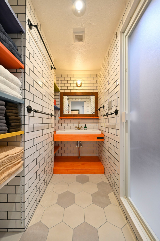 Inspiration för mellanstora asiatiska oranget badrum med dusch, med öppna hyllor, grå kakel, tunnelbanekakel, ett fristående handfat och grått golv