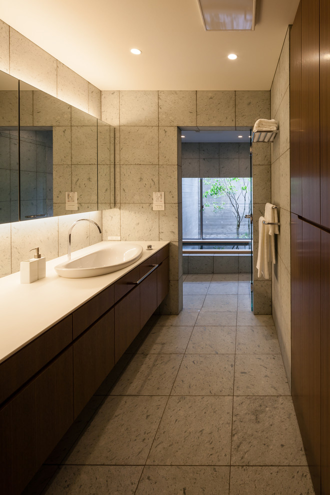 Cette image montre une salle de bain asiatique en bois foncé avec un mur gris, un lavabo posé et un carrelage gris.