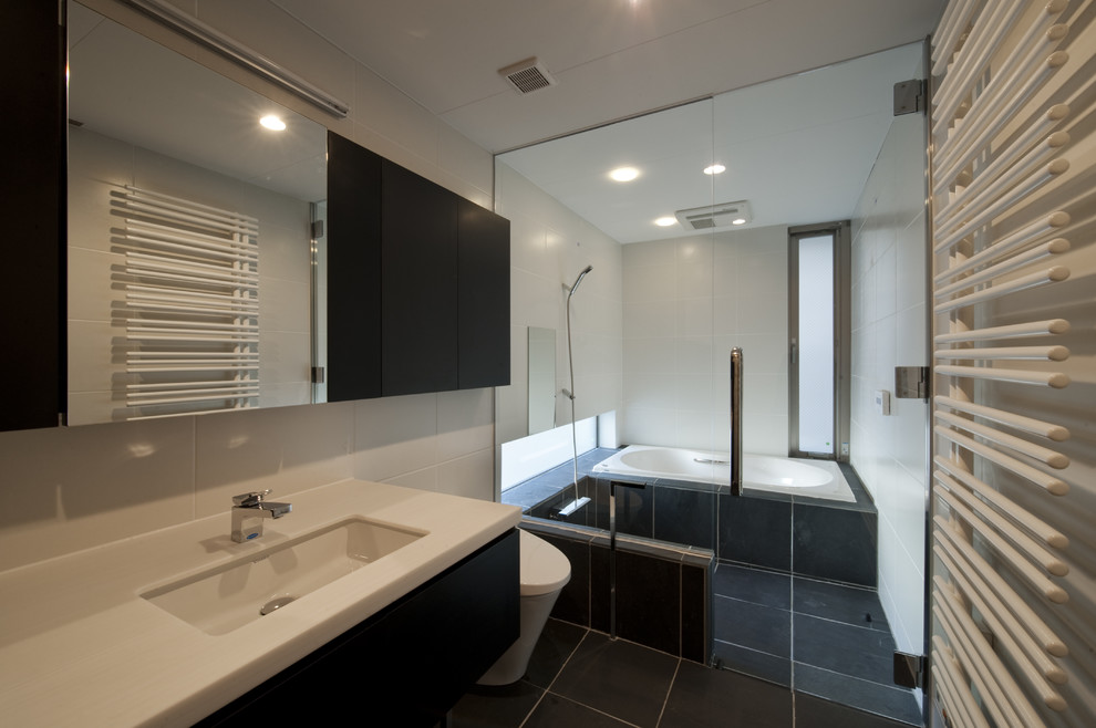 東京23区にあるコンテンポラリースタイルのおしゃれな浴室 (フラットパネル扉のキャビネット、黒いキャビネット、コーナー型浴槽、オープン型シャワー、白いタイル、白い壁、黒い床、オープンシャワー) の写真