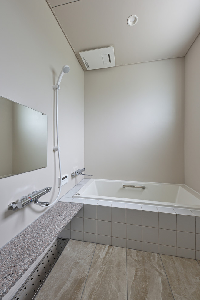 Aménagement d'une salle de bain moderne avec une baignoire d'angle, une douche ouverte, un mur gris, un sol gris et aucune cabine.