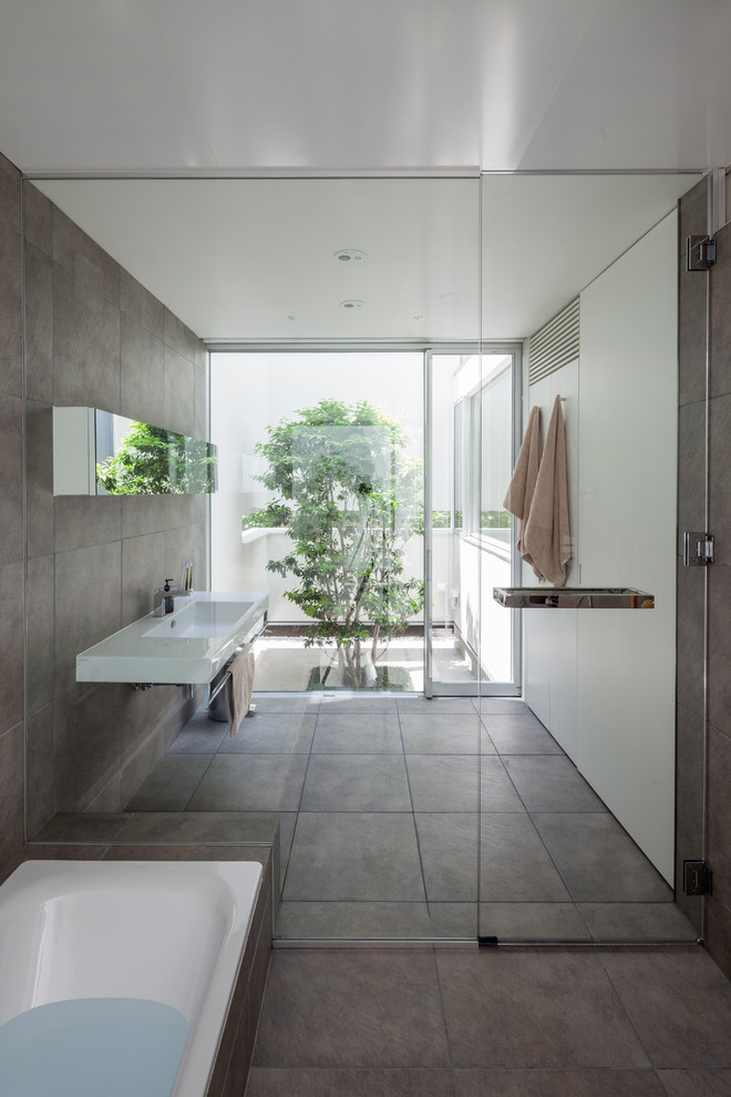 Imagen de cuarto de baño principal contemporáneo con lavabo suspendido, baldosas y/o azulejos grises, paredes blancas, bañera encastrada y ducha a ras de suelo