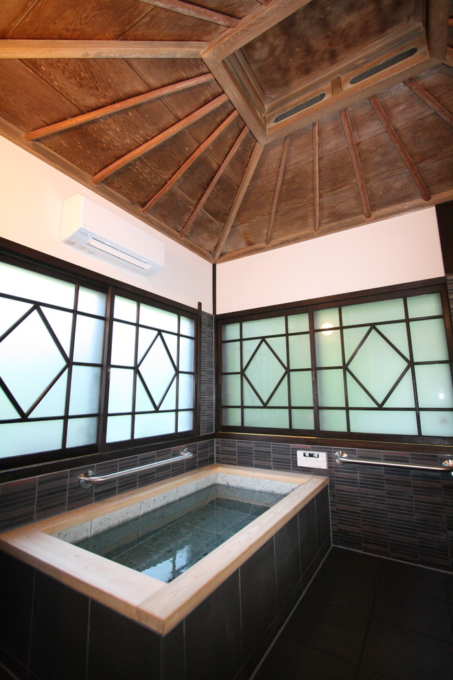Immagine di una stanza da bagno etnica con vasca ad angolo, pareti bianche e pavimento nero