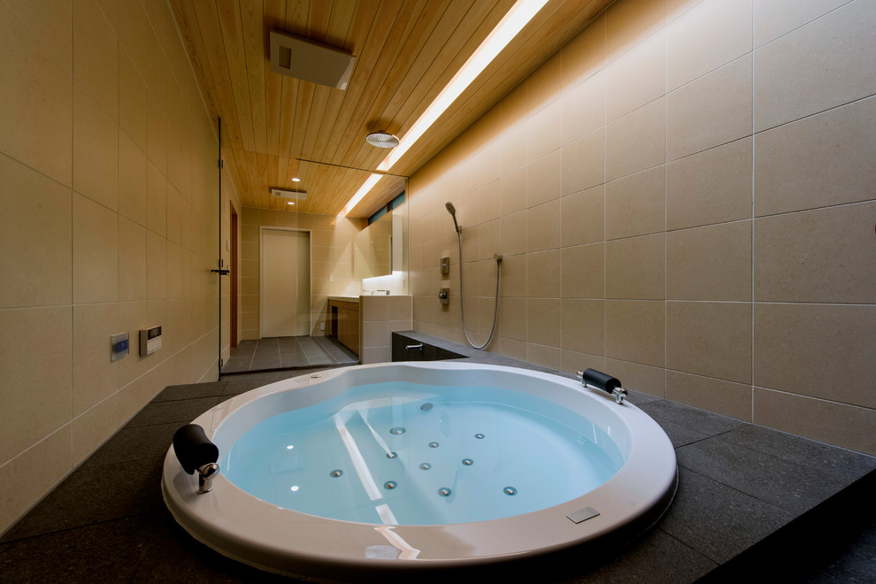 和風のおしゃれな浴室 (大型浴槽、ベージュのタイル、磁器タイル、ベージュの壁、磁器タイルの床、黒い床) の写真