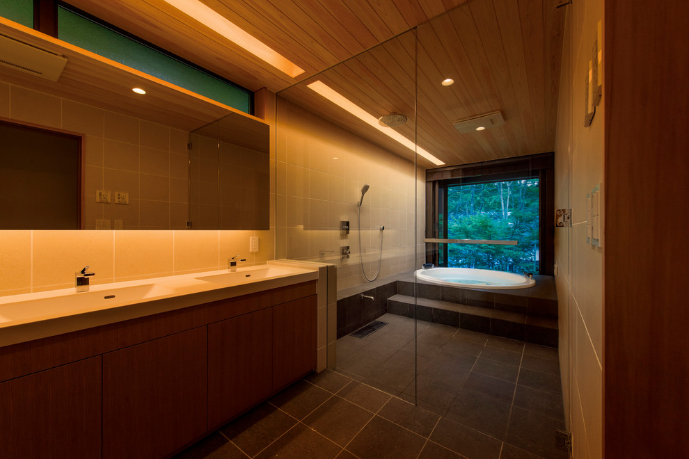Immagine di una stanza da bagno etnica con vasca idromassaggio, piastrelle beige, piastrelle in gres porcellanato, pareti beige, pavimento in gres porcellanato e pavimento nero