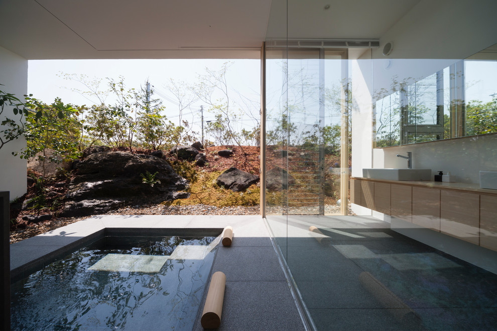 Esempio di una stanza da bagno design con ante lisce, ante in legno chiaro, vasca idromassaggio, pareti bianche e lavabo a bacinella