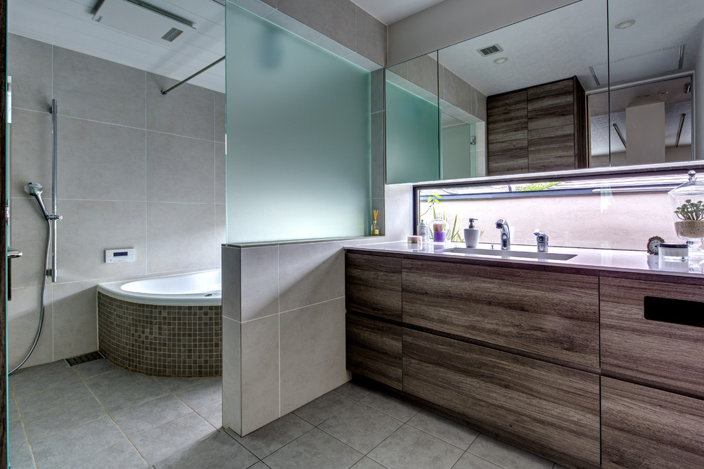 На фото: ванная комната в современном стиле с плоскими фасадами, серыми фасадами, угловой ванной, открытым душем, серыми стенами, монолитной раковиной, серым полом и открытым душем