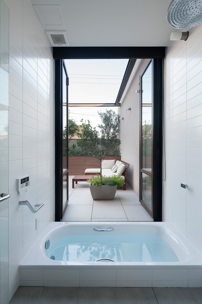 Diseño de cuarto de baño minimalista con bañera encastrada, ducha abierta, baldosas y/o azulejos blancos, paredes blancas, suelo gris y ducha abierta