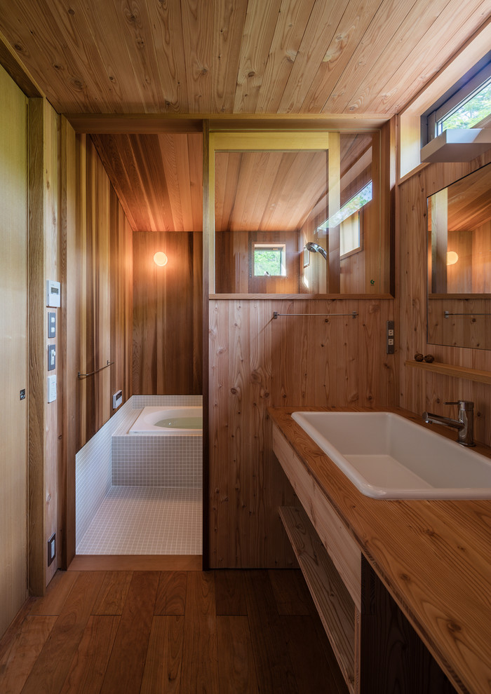 他の地域にある中くらいな北欧スタイルのおしゃれな浴室 (オープンシェルフ、茶色い壁、無垢フローリング、オーバーカウンターシンク、木製洗面台、茶色い床) の写真