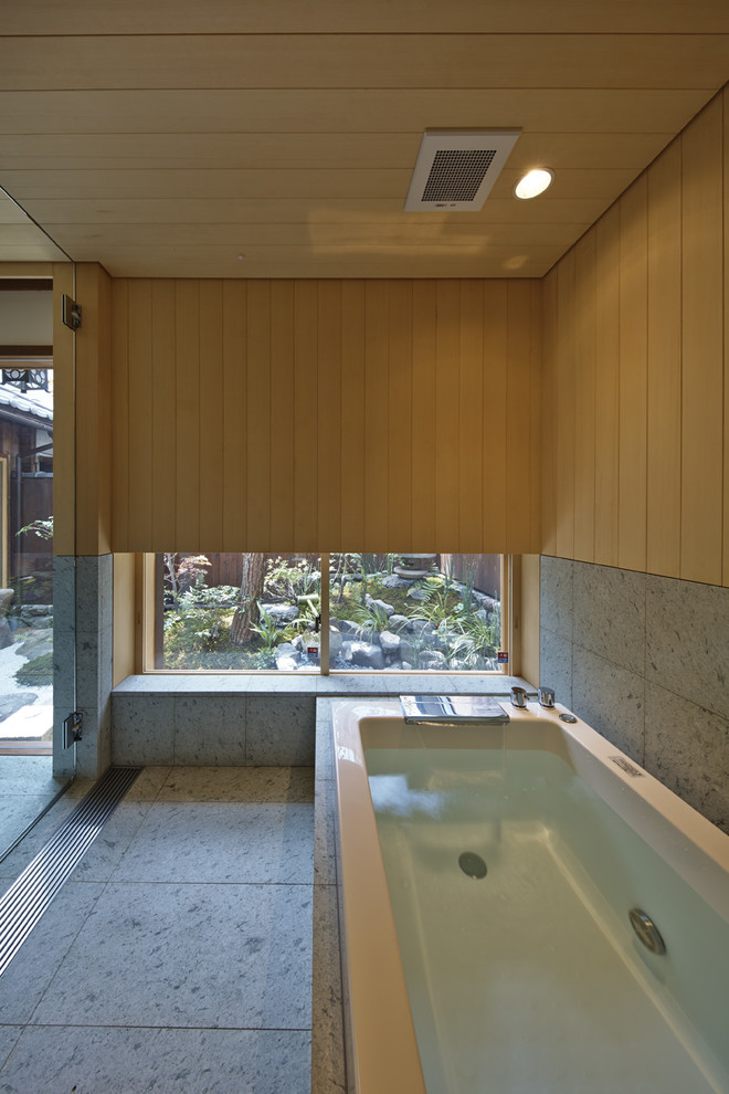 Asiatisk inredning av ett badrum, med ett hörnbadkar och grått golv