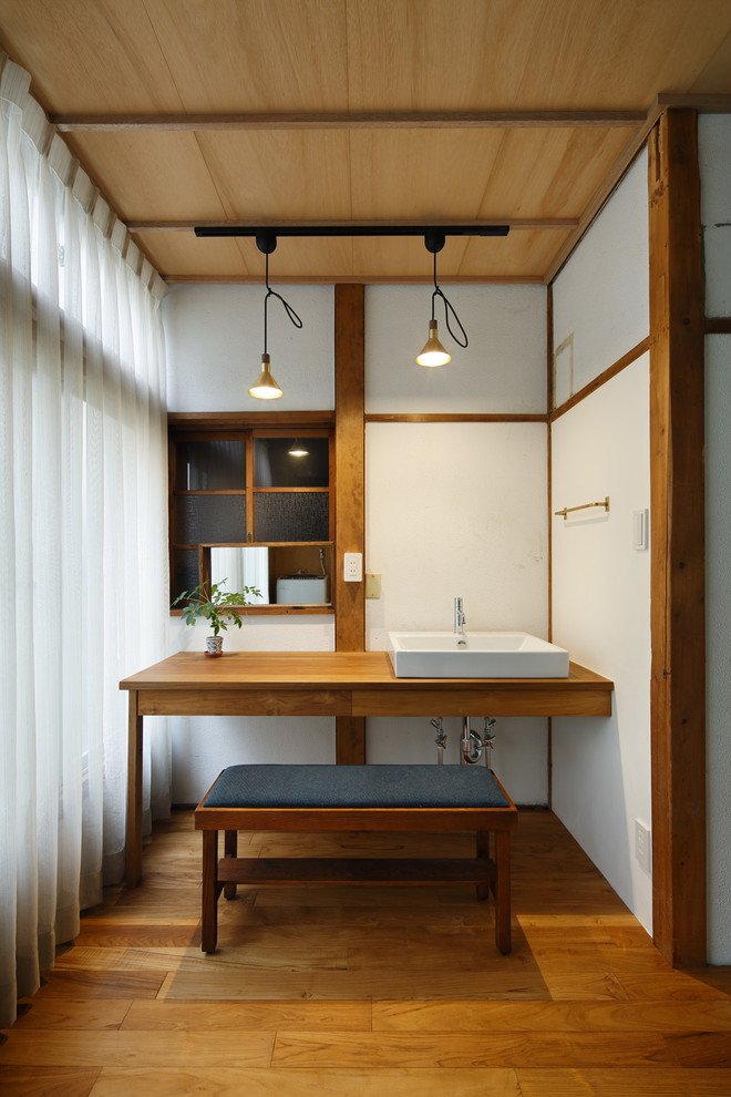 Foto de cuarto de baño principal asiático con armarios abiertos, puertas de armario de madera oscura, paredes blancas, suelo de madera en tonos medios, lavabo sobreencimera y encimera de madera