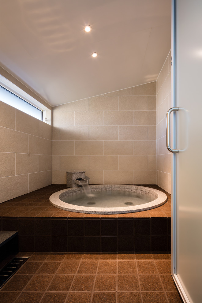 На фото: ванная комната в современном стиле с накладной ванной, бежевой плиткой, бежевыми стенами и коричневым полом с