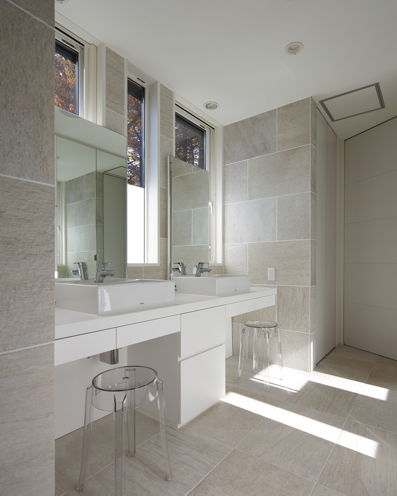 Esempio di una stanza da bagno minimalista con lavabo a bacinella, ante lisce, piastrelle beige, pareti beige, pavimento con piastrelle in ceramica e ante bianche