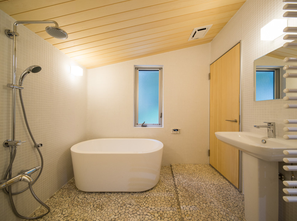 Asiatisches Badezimmer mit freistehender Badewanne, offener Dusche, weißer Wandfarbe, Kiesel-Bodenfliesen, Sockelwaschbecken, braunem Boden und offener Dusche in Sonstige