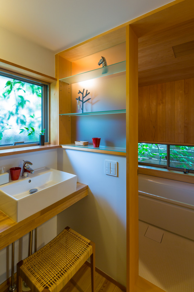 This is an example of a small modern ensuite wet room bathroom in Other with a built in vanity unit, open cabinets, medium wood cabinets, white walls, a built-in sink, beige floors, beige worktops and a single sink.