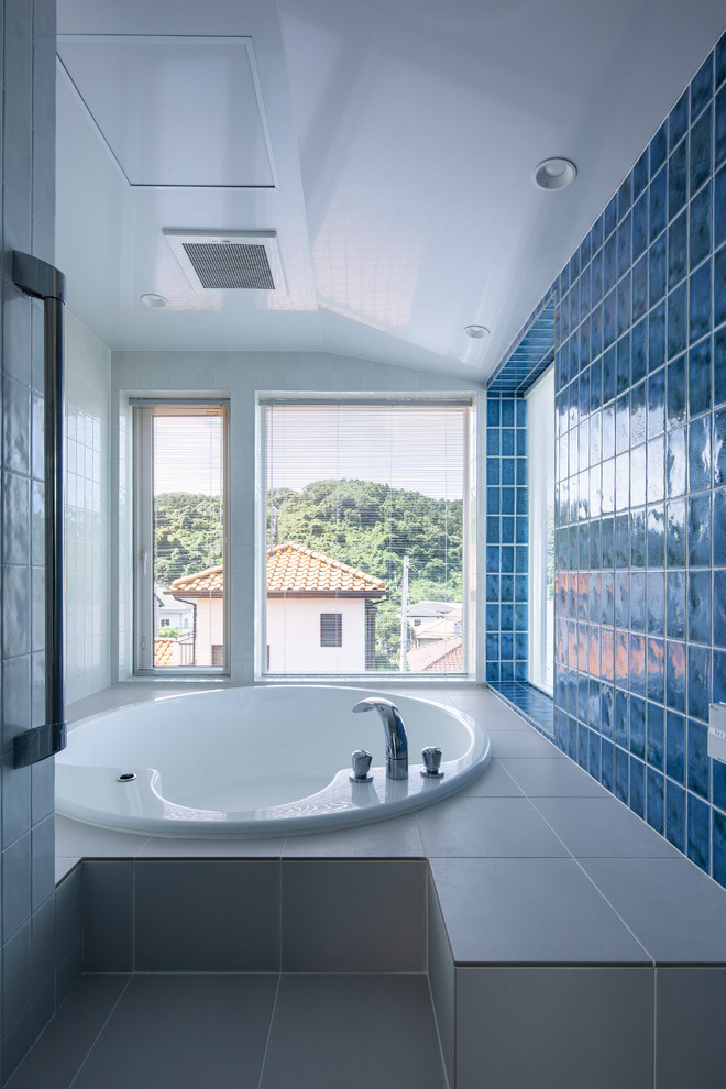 На фото: главная ванная комната среднего размера в стиле модернизм с гидромассажной ванной, душевой комнатой, синей плиткой, керамогранитной плиткой, синими стенами, полом из керамогранита и белым полом