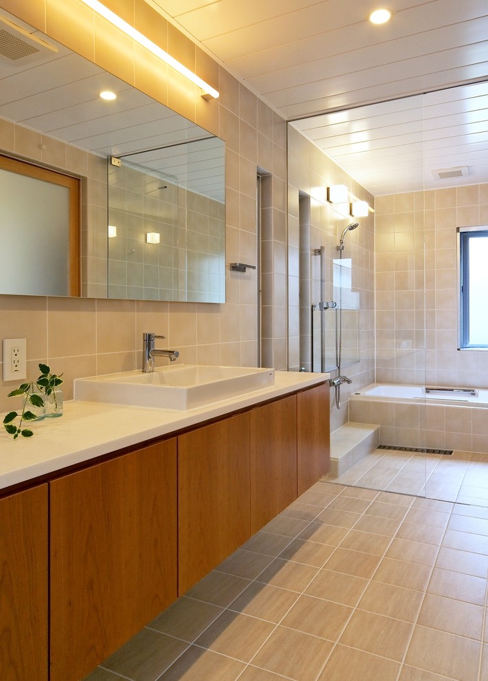 Esempio di una stanza da bagno contemporanea con ante lisce, ante in legno scuro, vasca da incasso, piastrelle beige, lavabo a bacinella, pavimento beige e top bianco