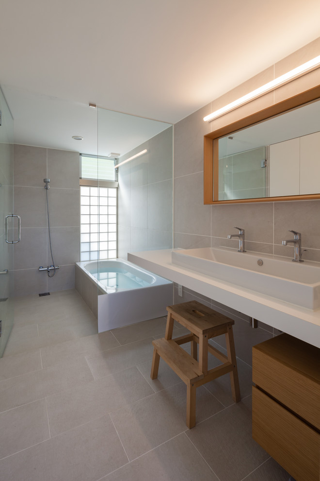 Esempio di una stanza da bagno minimalista con vasca ad angolo, doccia aperta, piastrelle grigie, pareti grigie, pavimento grigio e doccia aperta