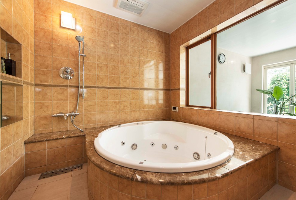 Aménagement d'une salle de bain méditerranéenne avec une baignoire d'angle, une douche ouverte, un carrelage marron, un mur marron, un sol beige et aucune cabine.