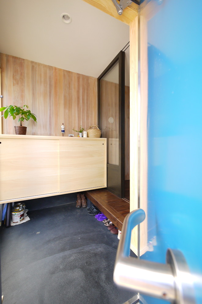 Idée de décoration pour une entrée bohème avec un couloir, un mur marron, sol en béton ciré, une porte simple, une porte bleue et un sol gris.