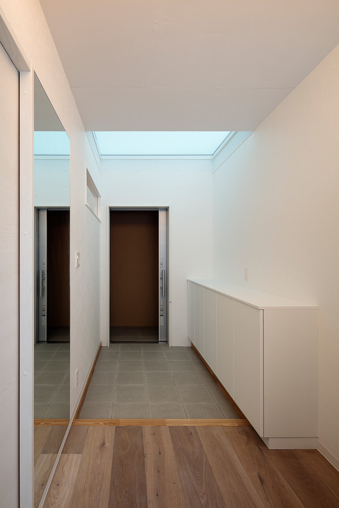 Esempio di un corridoio moderno di medie dimensioni con pareti bianche, pavimento in gres porcellanato, una porta scorrevole, una porta grigia e pavimento verde