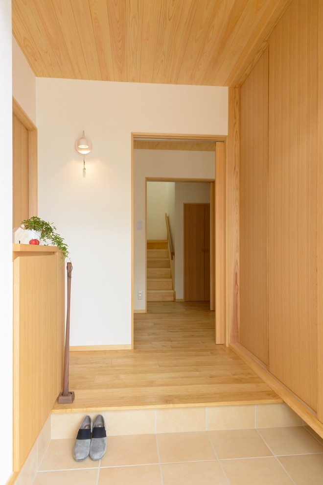 Photo of a medium sized scandinavian hallway in Other with white walls, medium hardwood flooring, a single front door and a medium wood front door.