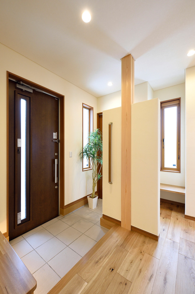 他の地域にある中くらいなおしゃれな玄関ホール (白い壁、無垢フローリング、濃色木目調のドア) の写真