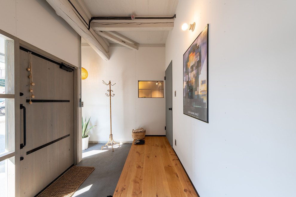 Industrial Foyer mit weißer Wandfarbe, braunem Holzboden, Einzeltür, grauer Haustür und braunem Boden in Sonstige