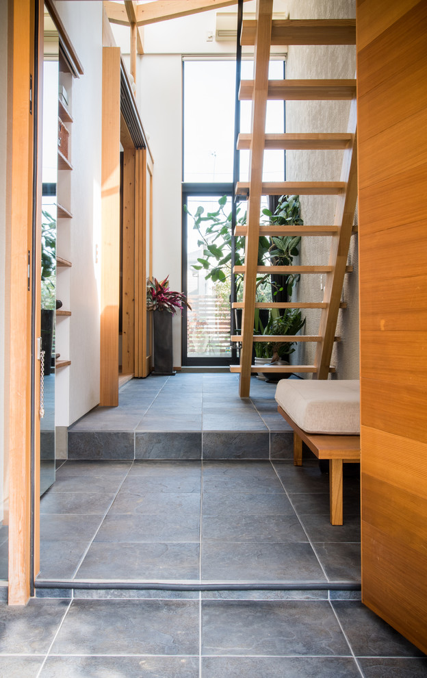 Idée de décoration pour une entrée minimaliste de taille moyenne avec un couloir, un mur blanc, un sol en carrelage de porcelaine, une porte simple, une porte en bois brun et un sol gris.