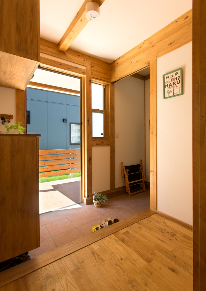 Ejemplo de hall de estilo zen con paredes blancas, suelo de baldosas de terracota y suelo marrón