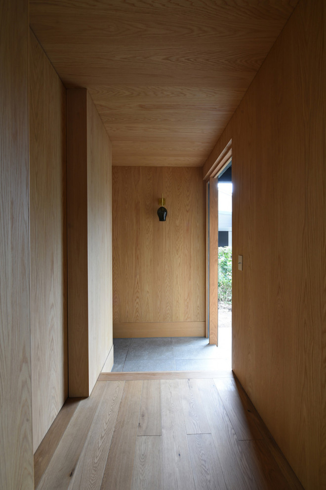 Идея дизайна: узкая прихожая среднего размера в стиле модернизм с светлым паркетным полом, одностворчатой входной дверью, входной дверью из светлого дерева, деревянным потолком и деревянными стенами