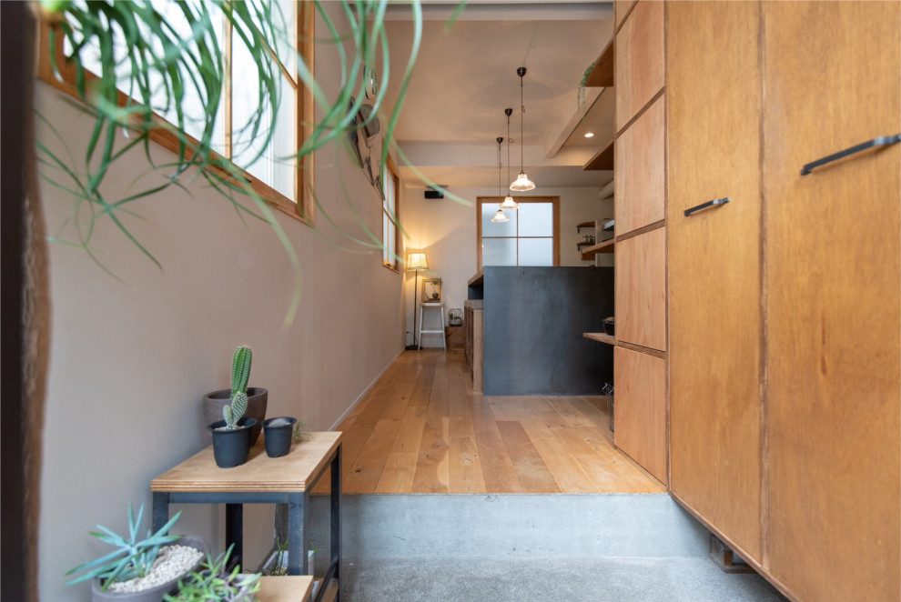 Expansive retro entrance in Tokyo with beige walls, concrete flooring, a single front door and grey floors.