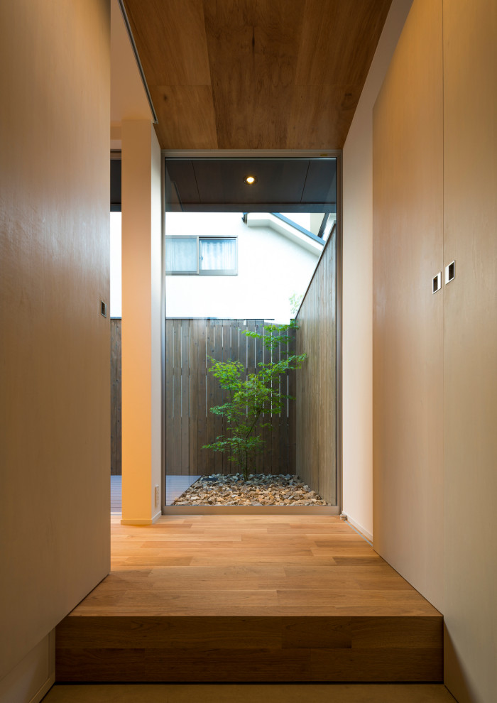 Diseño de hall escandinavo pequeño con paredes blancas, suelo de madera en tonos medios, puerta simple, puerta de madera oscura, suelo beige, papel pintado y panelado