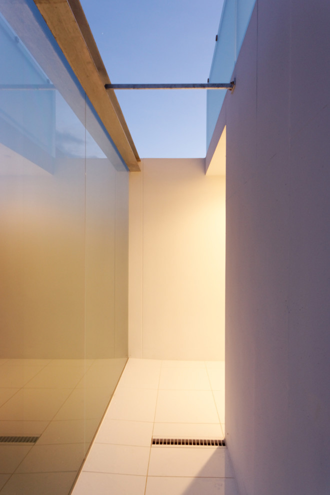 Foto de distribuidor minimalista de tamaño medio con paredes blancas, suelo de baldosas de cerámica, puerta simple, puerta metalizada y suelo blanco