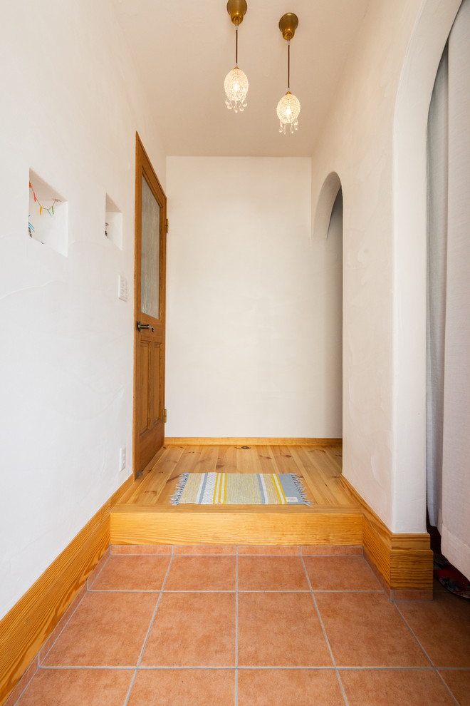 他の地域にあるアジアンスタイルのおしゃれな玄関ホール (白い壁、淡色無垢フローリング、濃色木目調のドア、マルチカラーの床) の写真