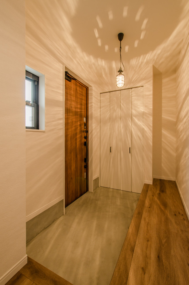 Immagine di un piccolo corridoio industriale con pareti bianche, pavimento in cemento, una porta singola, una porta in legno bruno, pavimento grigio, soffitto in carta da parati, carta da parati e armadio