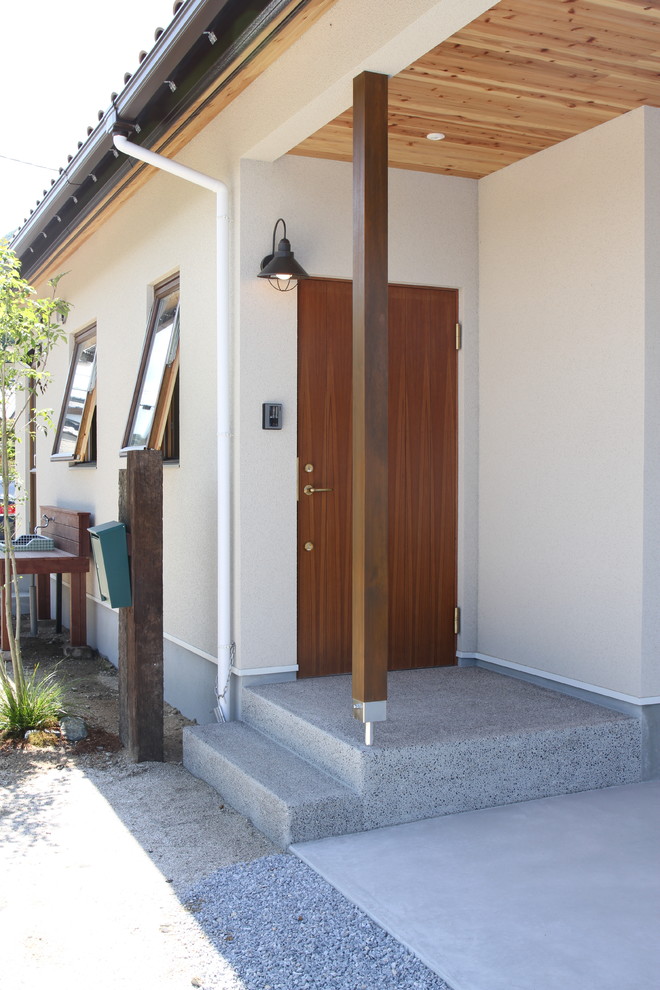 他の地域にあるシャビーシック調のおしゃれな玄関 (ベージュの壁、濃色木目調のドア、グレーの床) の写真