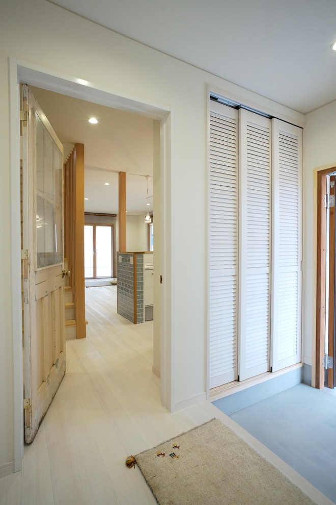 Imagen de hall nórdico con paredes blancas, suelo de madera clara, puerta simple, puerta de madera en tonos medios y suelo blanco