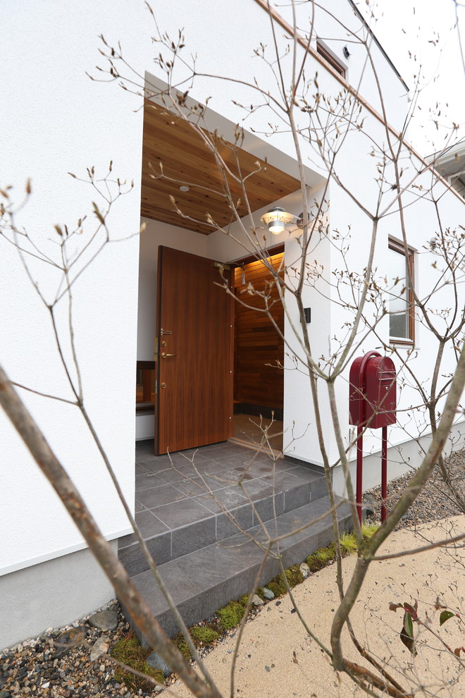Idée de décoration pour une porte d'entrée asiatique avec un mur blanc, un sol en carrelage de porcelaine, une porte simple et une porte marron.