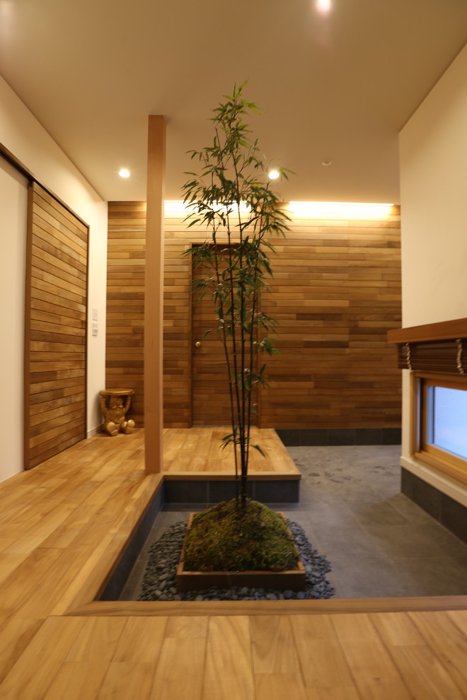 Diseño de hall asiático con paredes blancas, suelo de madera oscura, puerta simple y puerta marrón