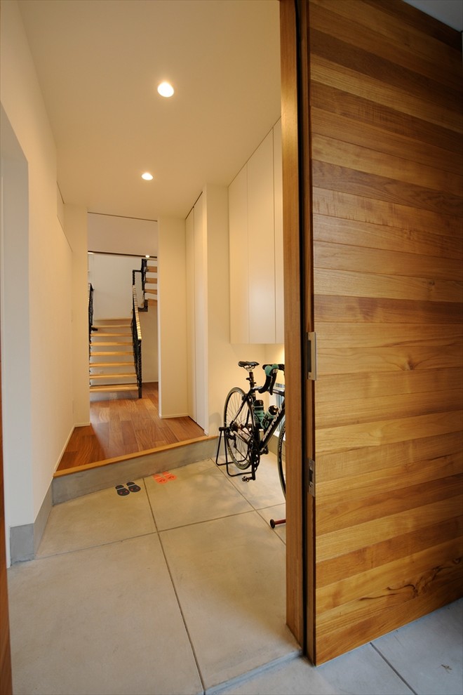 Inspiration pour une entrée minimaliste de taille moyenne avec un couloir, sol en béton ciré, une porte simple, un sol gris, un mur blanc et une porte métallisée.