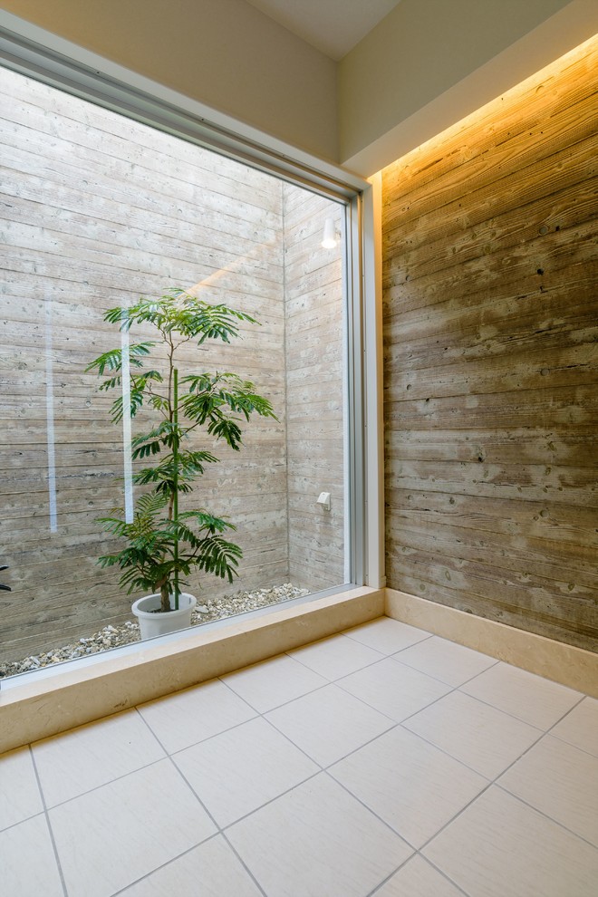Ispirazione per un corridoio minimalista con pareti bianche, pavimento in gres porcellanato, una porta a due ante, una porta in legno bruno e pavimento beige