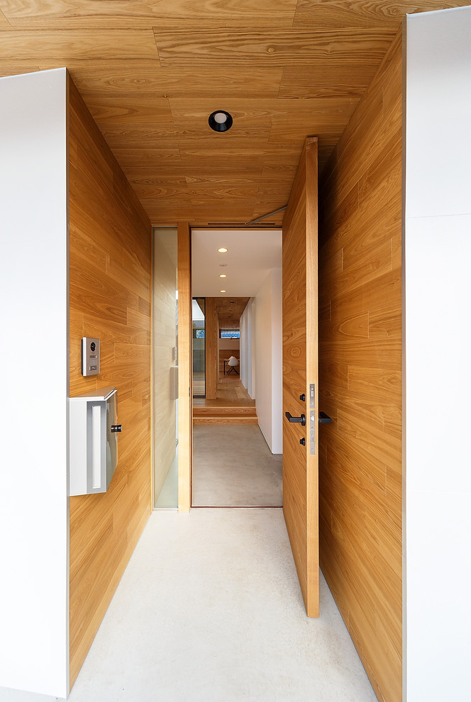 Inspiration för mellanstora moderna ingångspartier, med vita väggar, betonggolv, en enkeldörr, mellanmörk trädörr och grått golv
