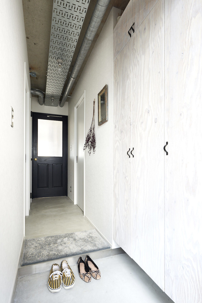 他の地域にあるインダストリアルスタイルのおしゃれな玄関ホール (白い壁、コンクリートの床、グレーの床) の写真