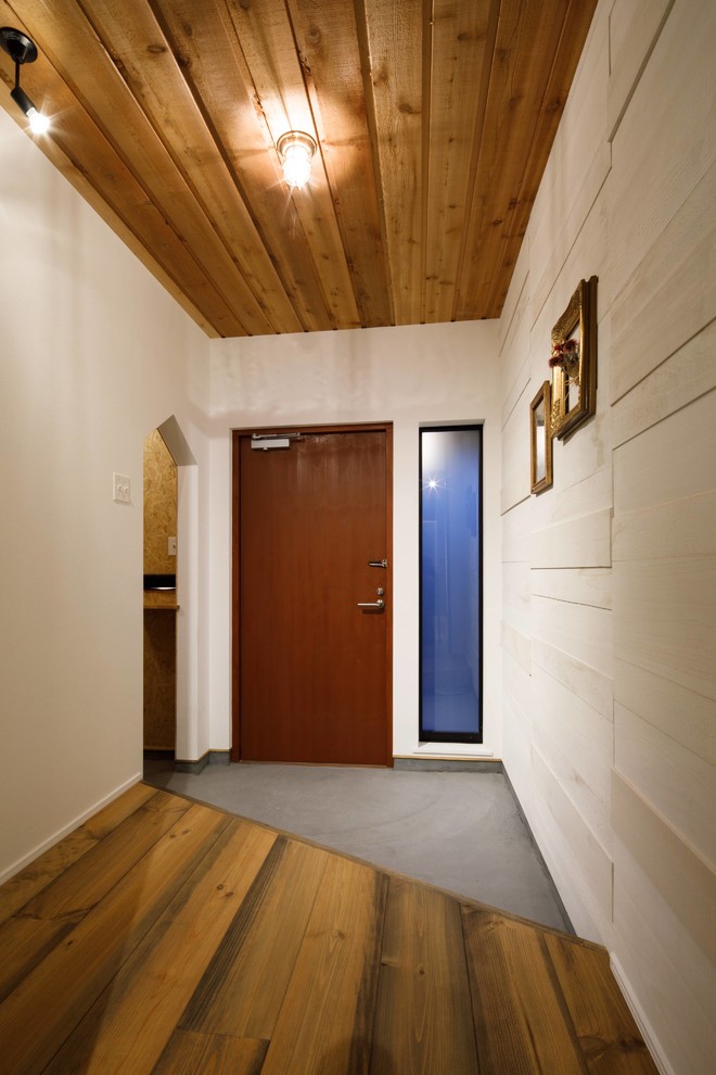 Источник вдохновения для домашнего уюта: узкая прихожая в стиле лофт с белыми стенами, бетонным полом, одностворчатой входной дверью, входной дверью из дерева среднего тона и серым полом