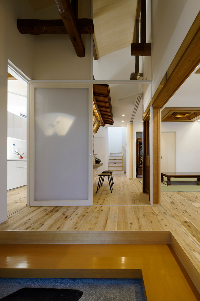This is an example of a medium sized world-inspired vestibule in Tokyo with white walls and a white front door.
