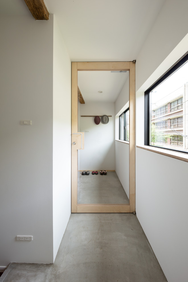 Foto de entrada asiática de tamaño medio con paredes blancas, suelo de cemento, puerta simple y puerta de madera clara