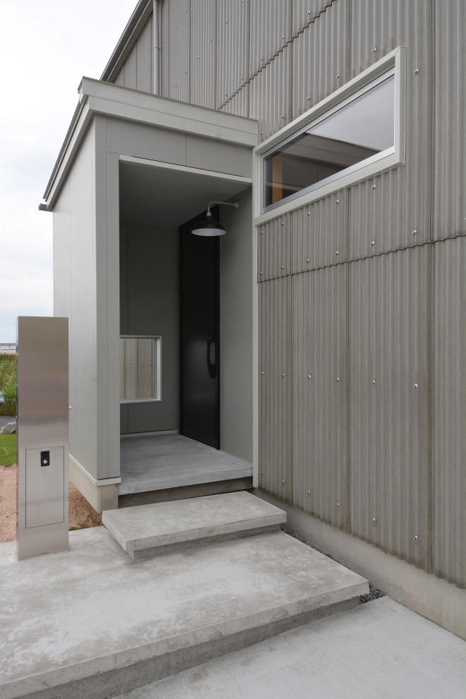 Immagine di una porta d'ingresso industriale di medie dimensioni con pareti grigie, pavimento in vinile, una porta singola, una porta nera, pavimento nero, soffitto in carta da parati e carta da parati