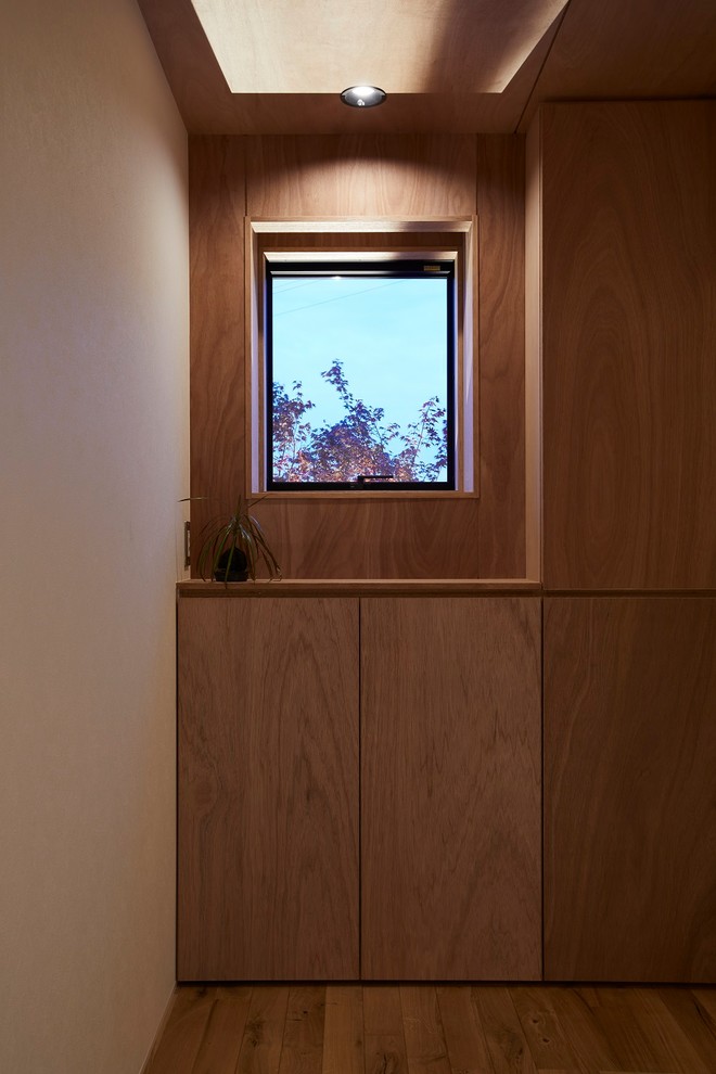 Ejemplo de hall minimalista de tamaño medio con paredes marrones, suelo de madera en tonos medios, puerta corredera, puerta de madera en tonos medios y suelo marrón